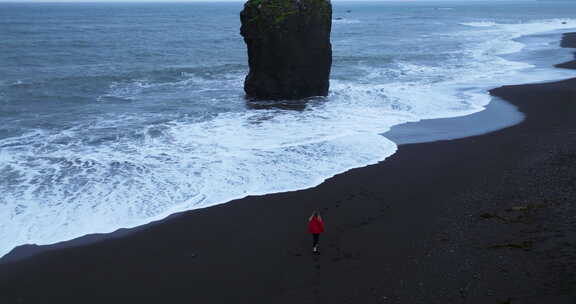 穿着红色夹克的女人在冰岛的莱克贾维克海滩