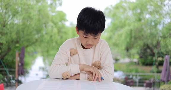 可爱的中国小男孩在户外认真学习写作业