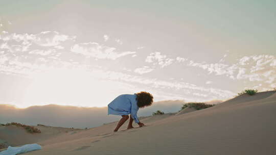 女舞者在沙丘上的夏日日落中投沙表演