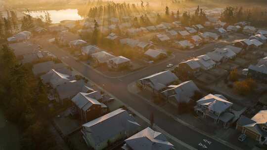 日出时屋顶被霜覆盖的郊区社区鸟瞰图。
