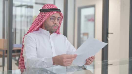 年轻的阿拉伯男子在工作中阅读文件视频素材模板下载