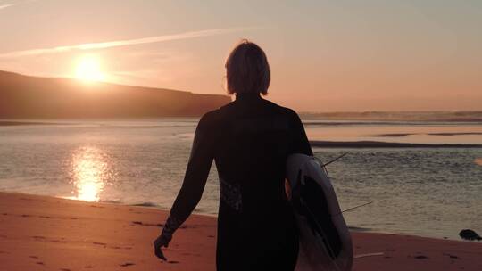 女人抱着冲浪板走向海边