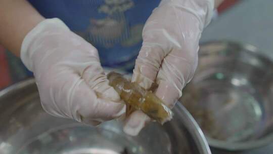 戴手套处理虾的手部特写