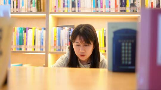 年轻女子图书馆在书架前翻看书本学习视频素材模板下载