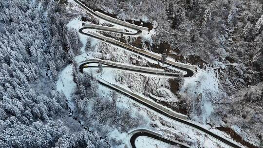 航拍雪后山林间蜿蜒曲折的公路