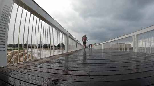 慢动作长腿男人在雨中不穿鞋跑过人行桥