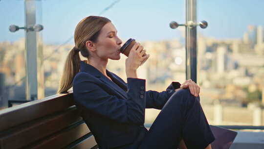 微笑的女人在办公室阳台上啜饮咖啡快乐的经