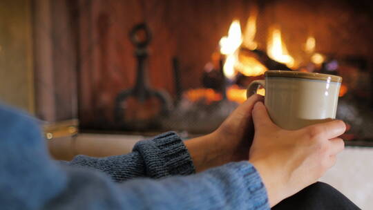 手捧一杯茶坐在壁炉前