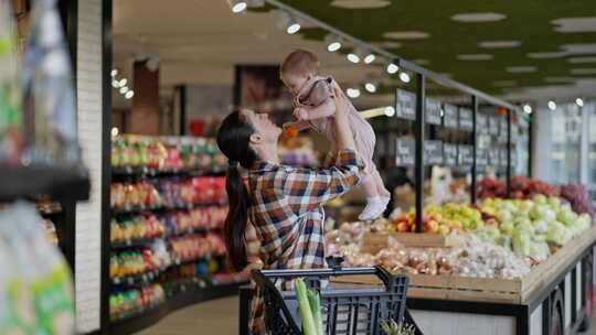 快乐的黑发女孩在一个格子衬衫抱着她的小婴