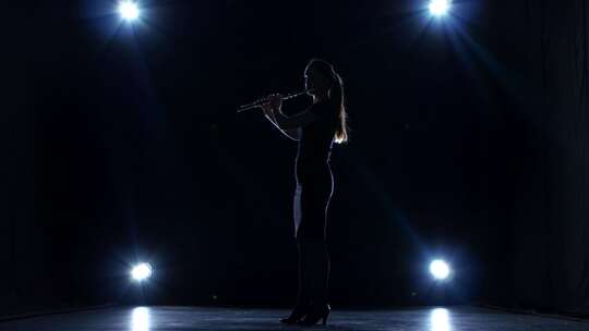 聚光灯下黑暗工作室的音乐家演奏长笛缓慢的