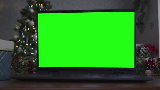 圣诞主题背景前桌子上的绿屏笔记本