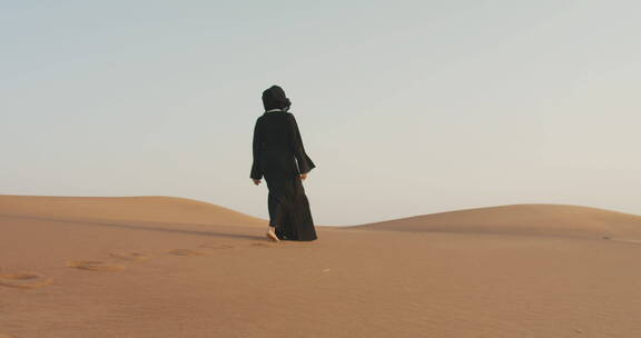 戴着头巾的女人赤脚在沙漠中行走