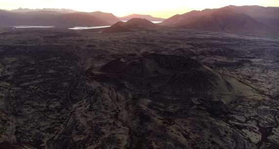 日落时贫瘠景观中湖泊附近的火山山脉