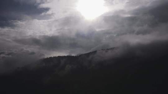 阳光穿过云层，盘旋在森林覆盖的山上