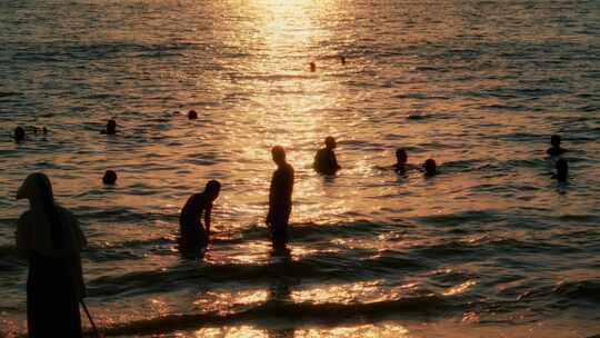 日落海边沙滩玩水人群夕阳波光粼粼剪影