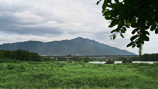 桂林漓江边的草地和远山下横跨漓江的铁路桥