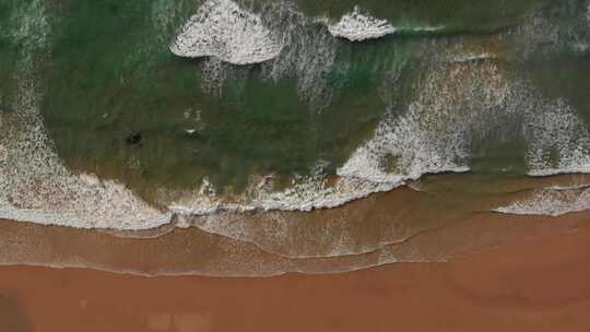 马洛海滩上空令人放松的空中，柔和的海浪拍打着金色的沙滩；葡萄牙