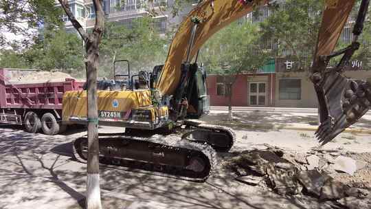 挖掘机揭去城区柏油路面装入渣土车视频素材模板下载