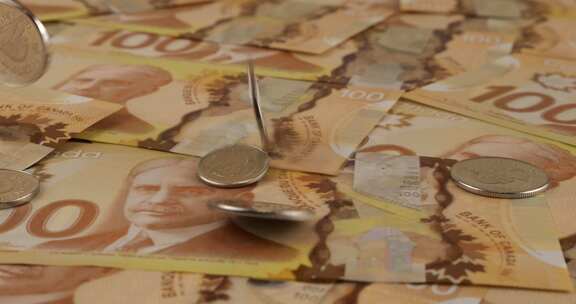 100美元聚合物纸币上掉落的加拿大硬币，上面有罗伯特·博登的肖像。慢动作