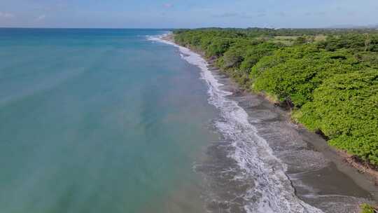 沿多岩石的帕伦克海滩和多米尼加共和国蓝色大海的风景优美的海岸线空中飞行
