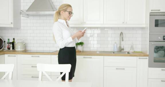 成功的女性在家里的厨房里使用手机