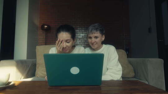 两个年轻女人在家一起放松时在笔记本电脑上看有趣的视频