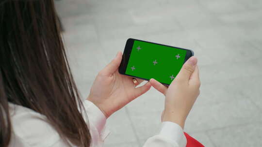 女性手在智能手机上观看色度键屏幕。视频素材模板下载