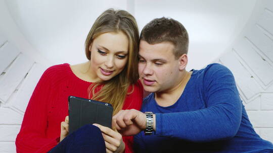 一对年轻夫妇看着平板电脑交流视频素材模板下载