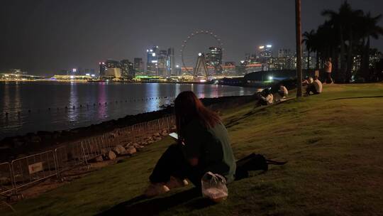 夜晚一个孤独女孩在海边坐着思考玩手机视频素材模板下载