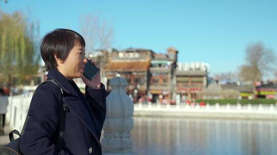 冬季在什刹海湖边使用手机的东方女性