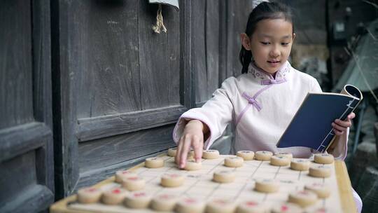 穿中国传统服饰下中国象棋的中国女孩
