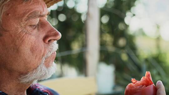 老人正在品尝番茄的特写镜头