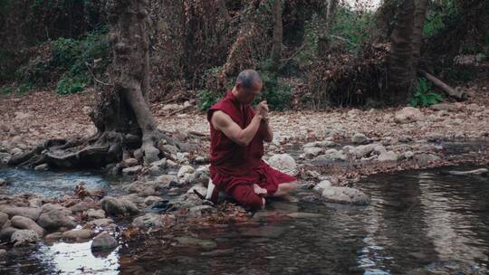 僧侣坐在河流边祈祷视频素材模板下载