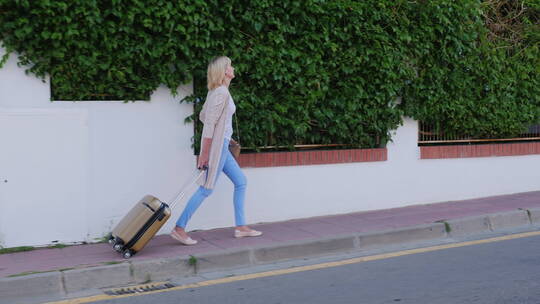 女人拉着行李箱走到酒店门口