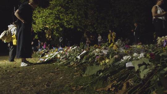 绿色公园哀悼者和花卉贡品的跟踪拍摄