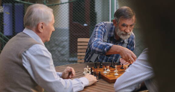 退休老人围着桌子下国际象棋