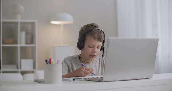 十几岁的男孩正在用耳机画画和听音乐，白天独自坐在家里，画画
