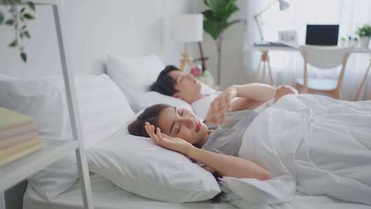 亚洲迷人的年轻夫妇躺在床上睡在卧室里。