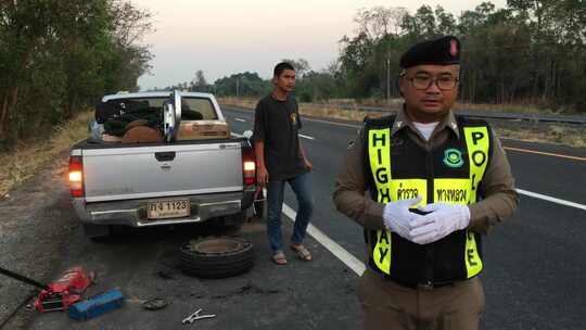 男子在高速公路警察的协助下更换扁平轮胎