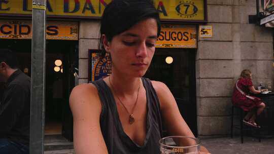 美丽的高加索女人在马德里（西班牙）的一家酒吧喝啤酒。坐在露台上的西班牙女孩
