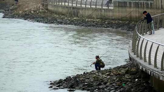 江面上大桥下有人在岸边钓鱼