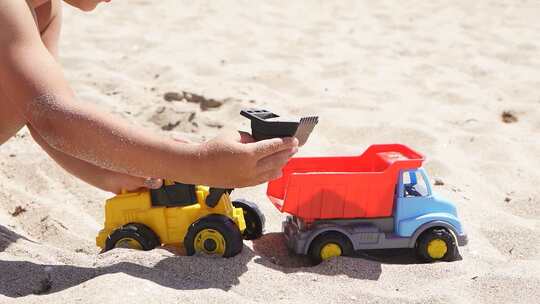 沙滩上玩塑料车的小男孩