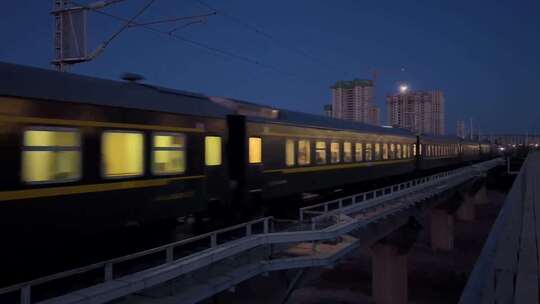 夜间火车行驶于城市铁轨上的画面