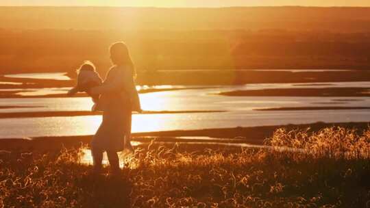 妈妈抱着小婴儿在夕阳下转圈玩耍视频素材模板下载