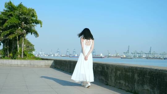 穿白色吊带长裙的女孩在江边吹风转圈素材