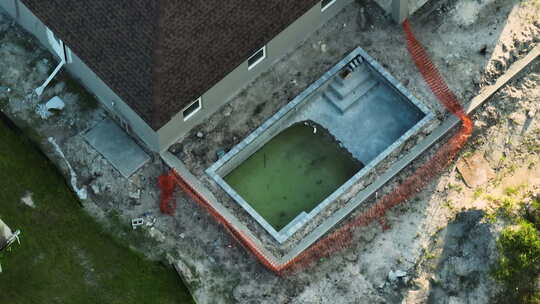 郊区私人住宅的鸟瞰图，游泳池安装和木制屋顶框架在下面
