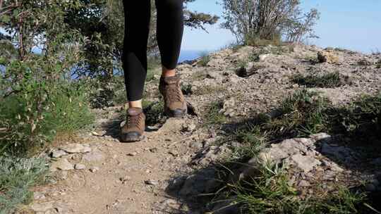 徒步登山妇女在悬崖顶上徒步的脚在岩石上行