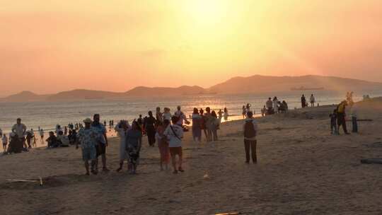 夕阳下热闹的海滩人群景象