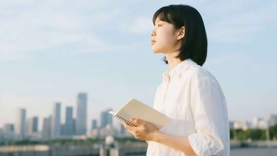 女子户外手持笔记本眺望远方