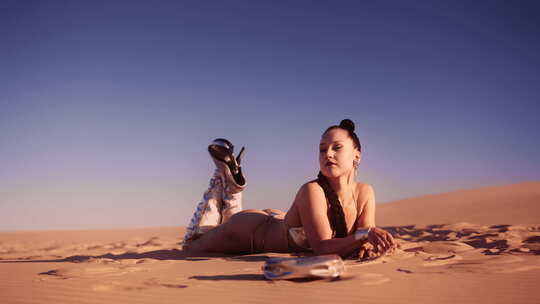 穿着比基尼和靴子躺在沙漠沙滩上的年轻女子